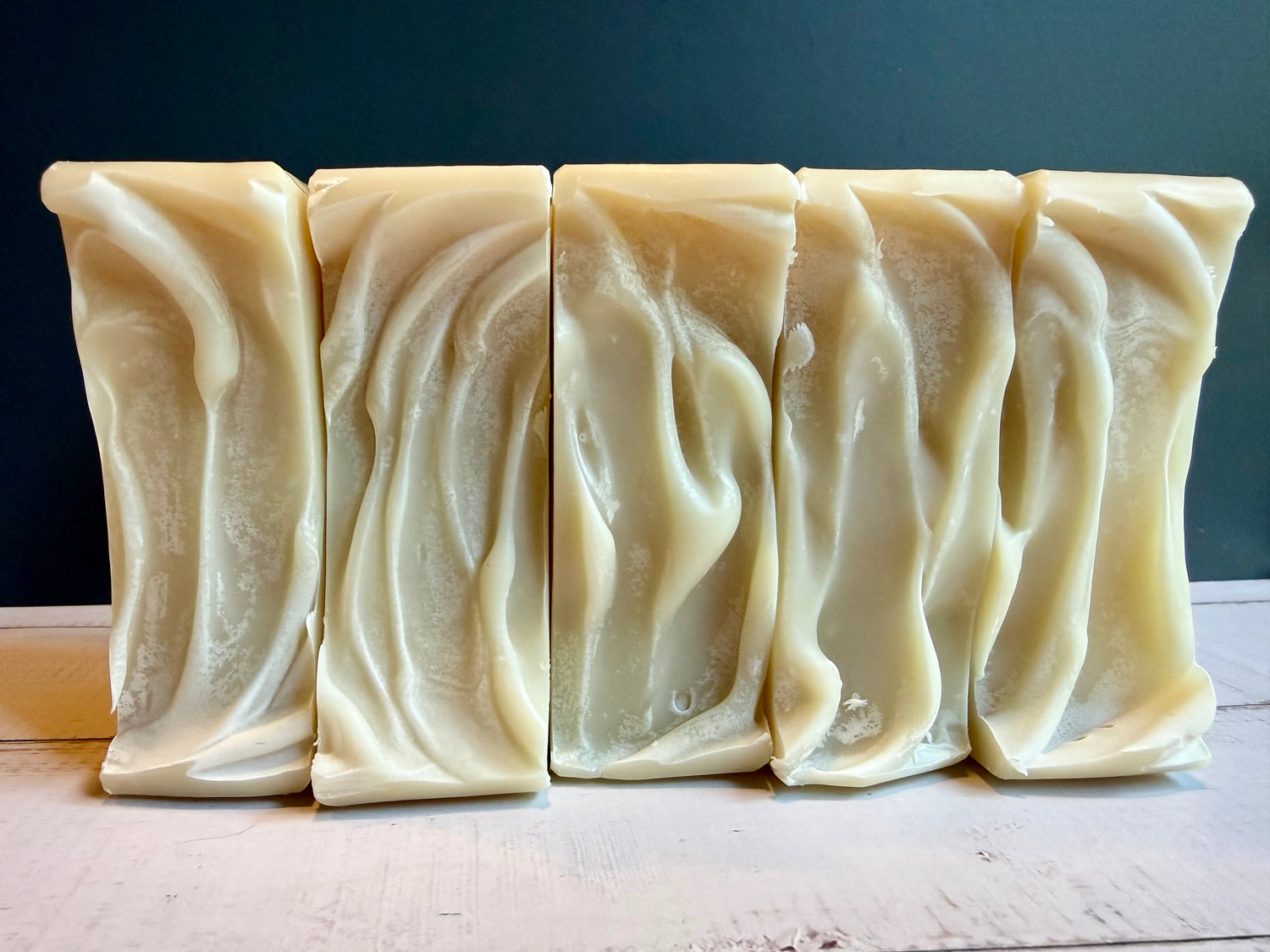 5 cream soap tops in a row on a wooden surface with a black background.
