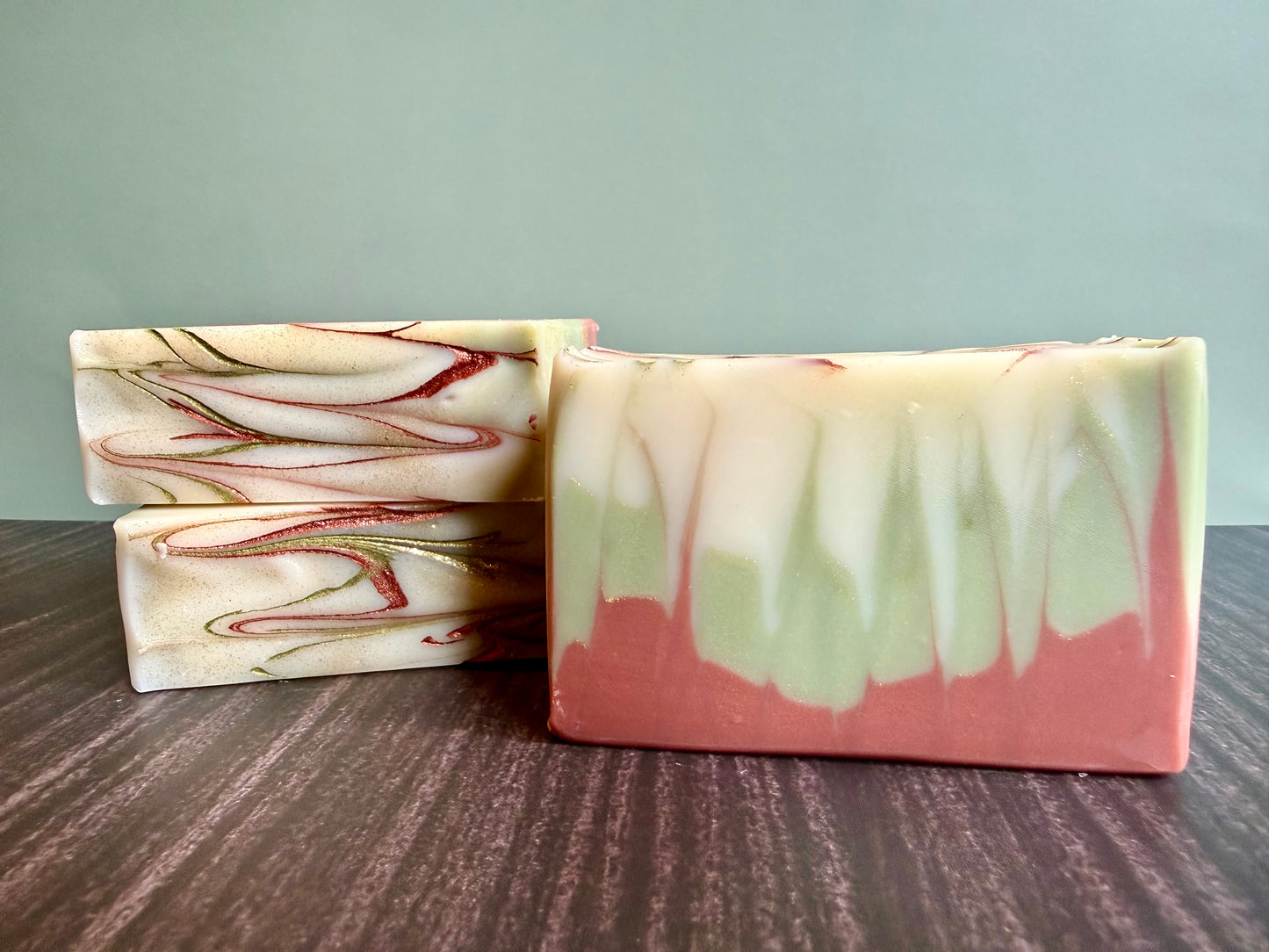 Two bars of marbled soap on a wooden surface with a neutral background