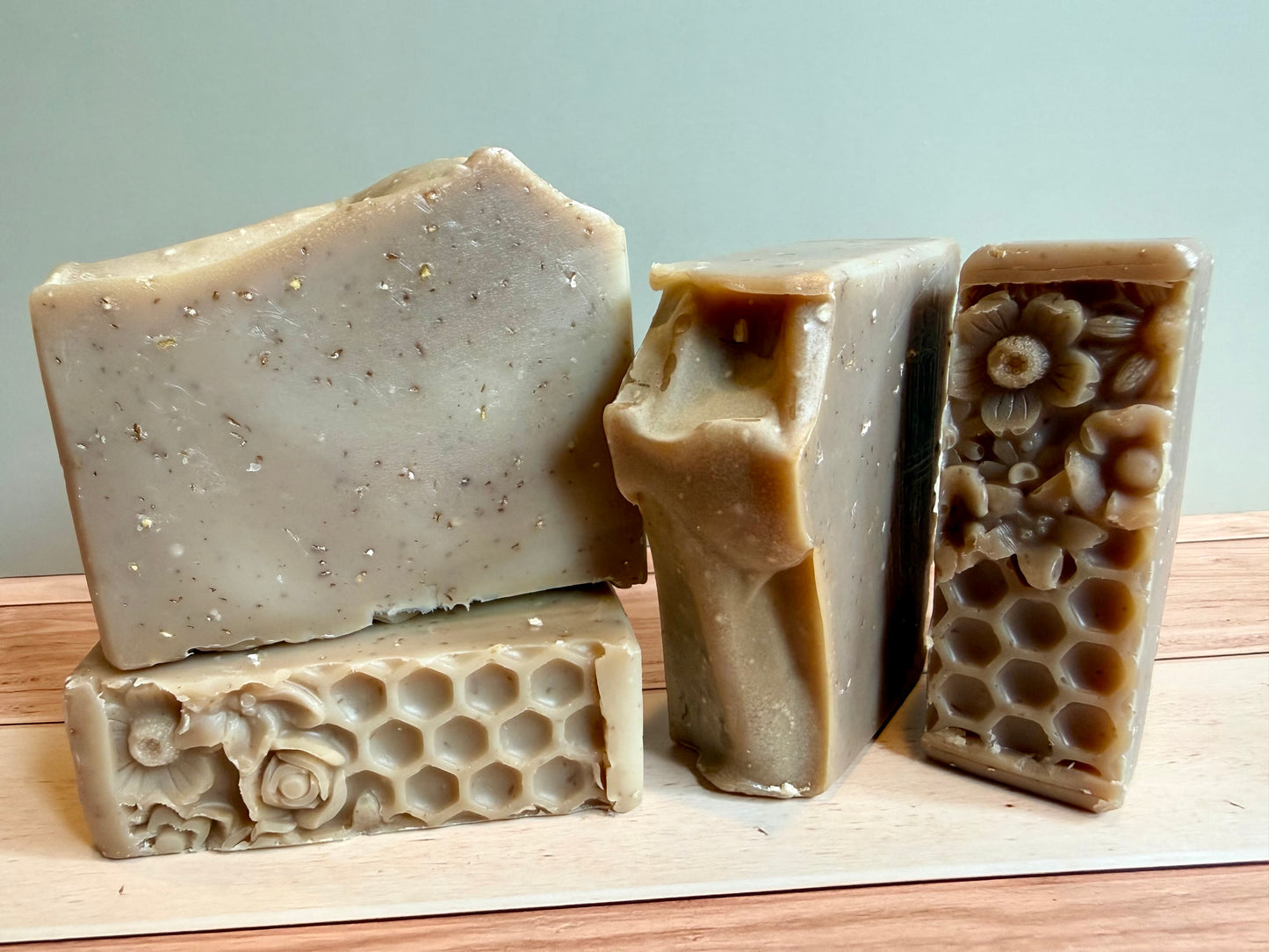 Four bars of tan oatmeal soap with a floral honeycomb bottom and mounded tops. 