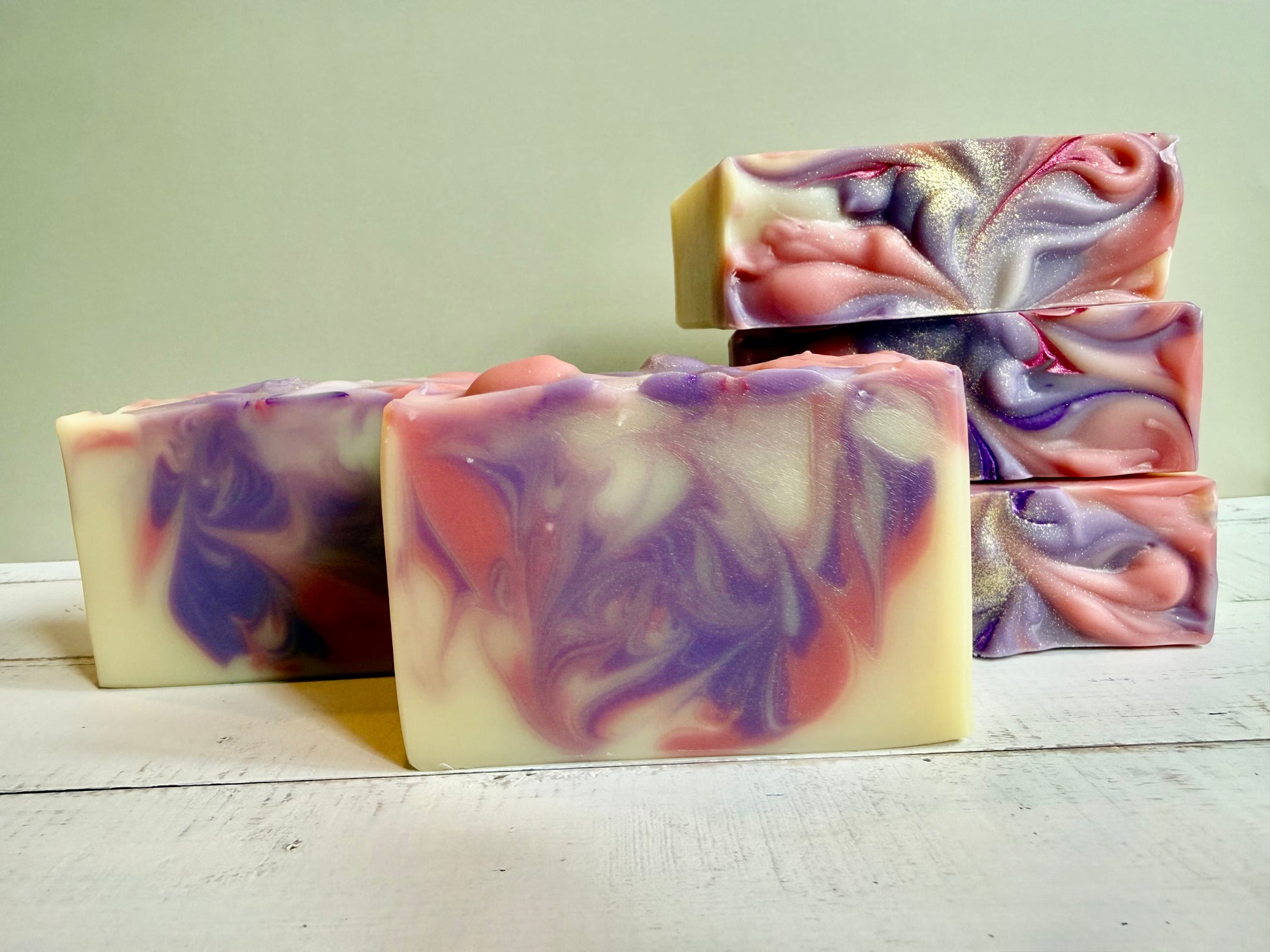Swirl-patterned soap bars on a light wooden surface with a neutral background