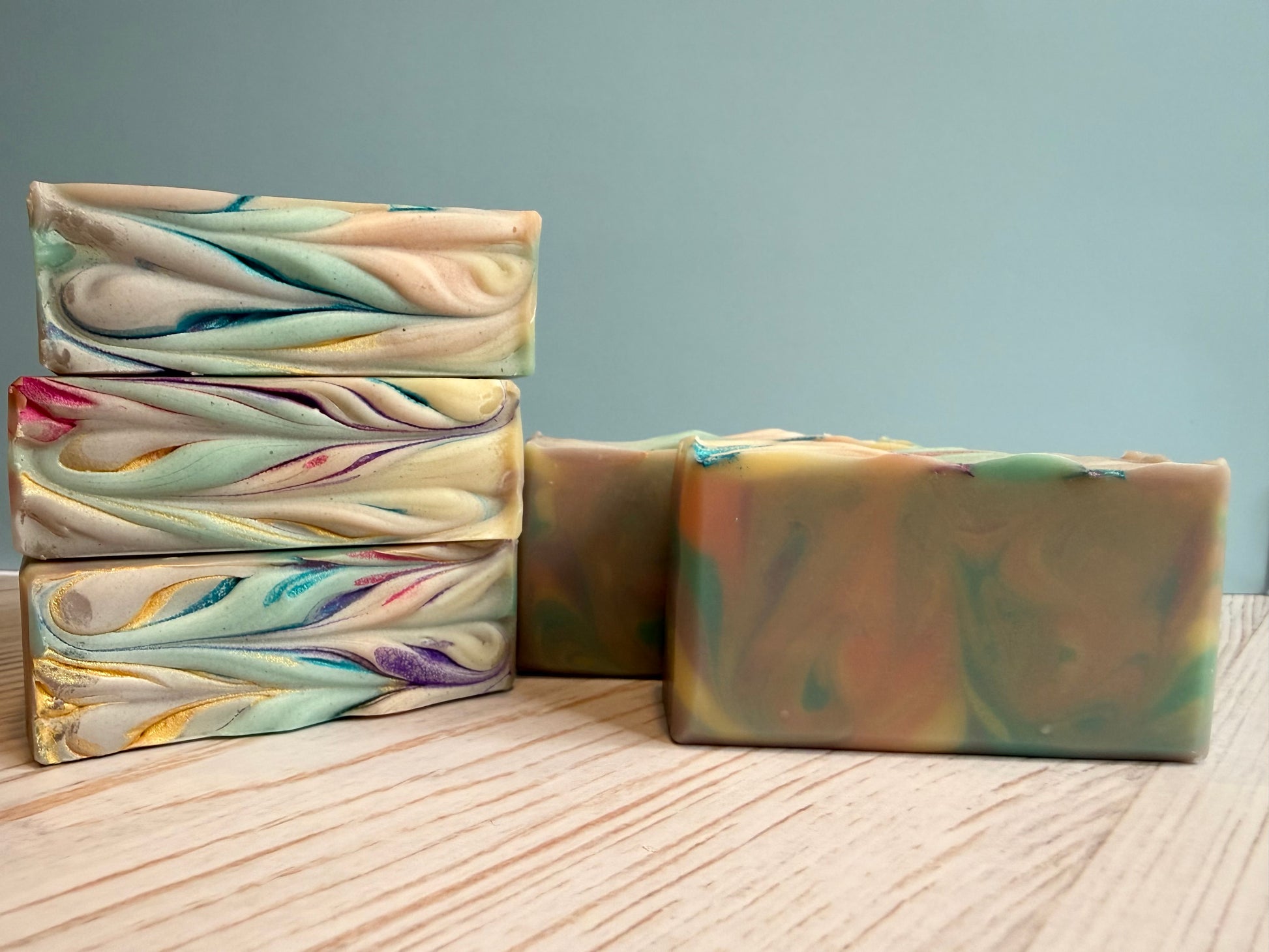 Three bars of multicolored soap on a wooden surface with a gray background