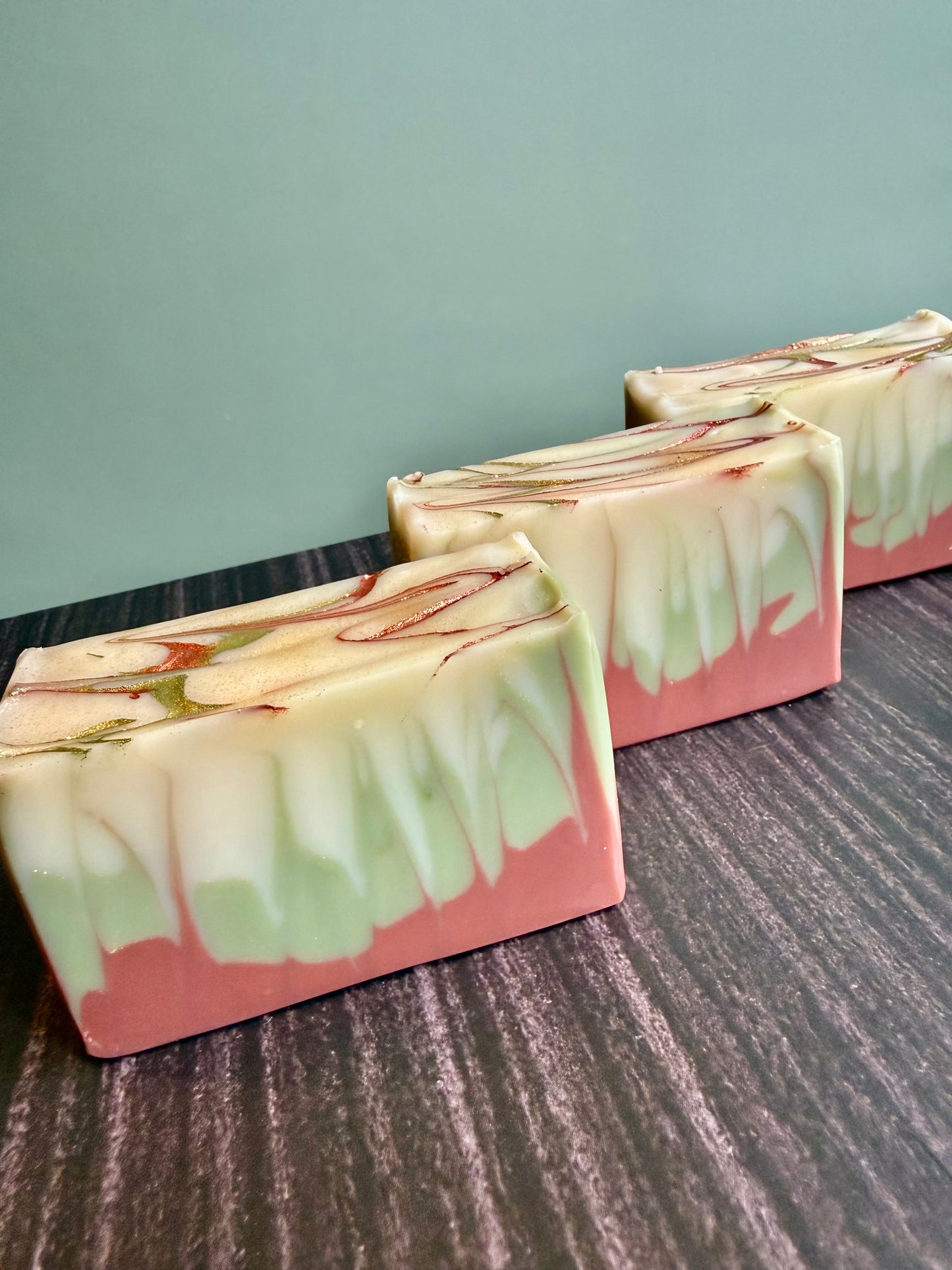 Three bars of soap with a marbled design on a textured surface.