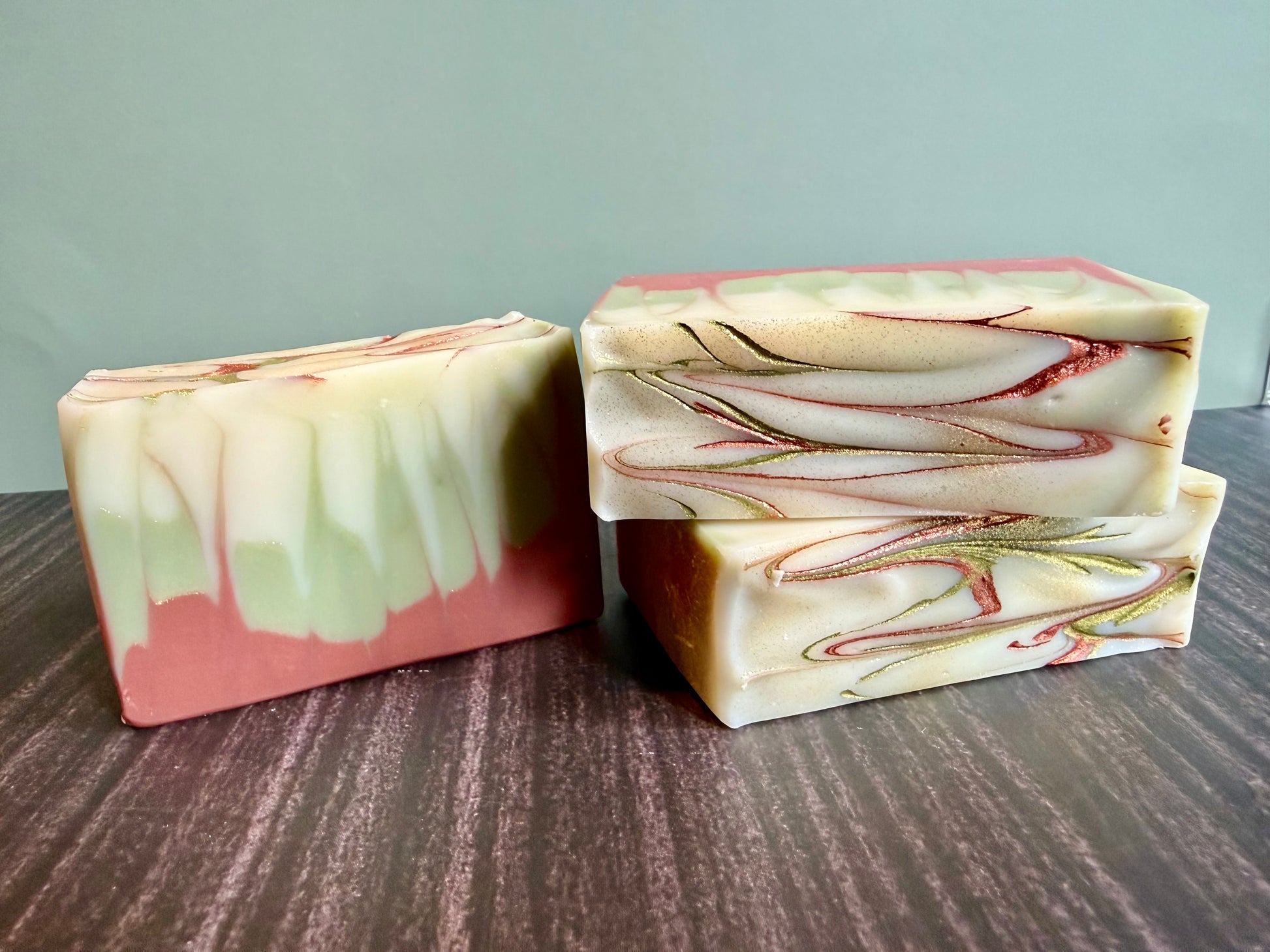Three marbled soap bars on a wooden surface with a neutral background