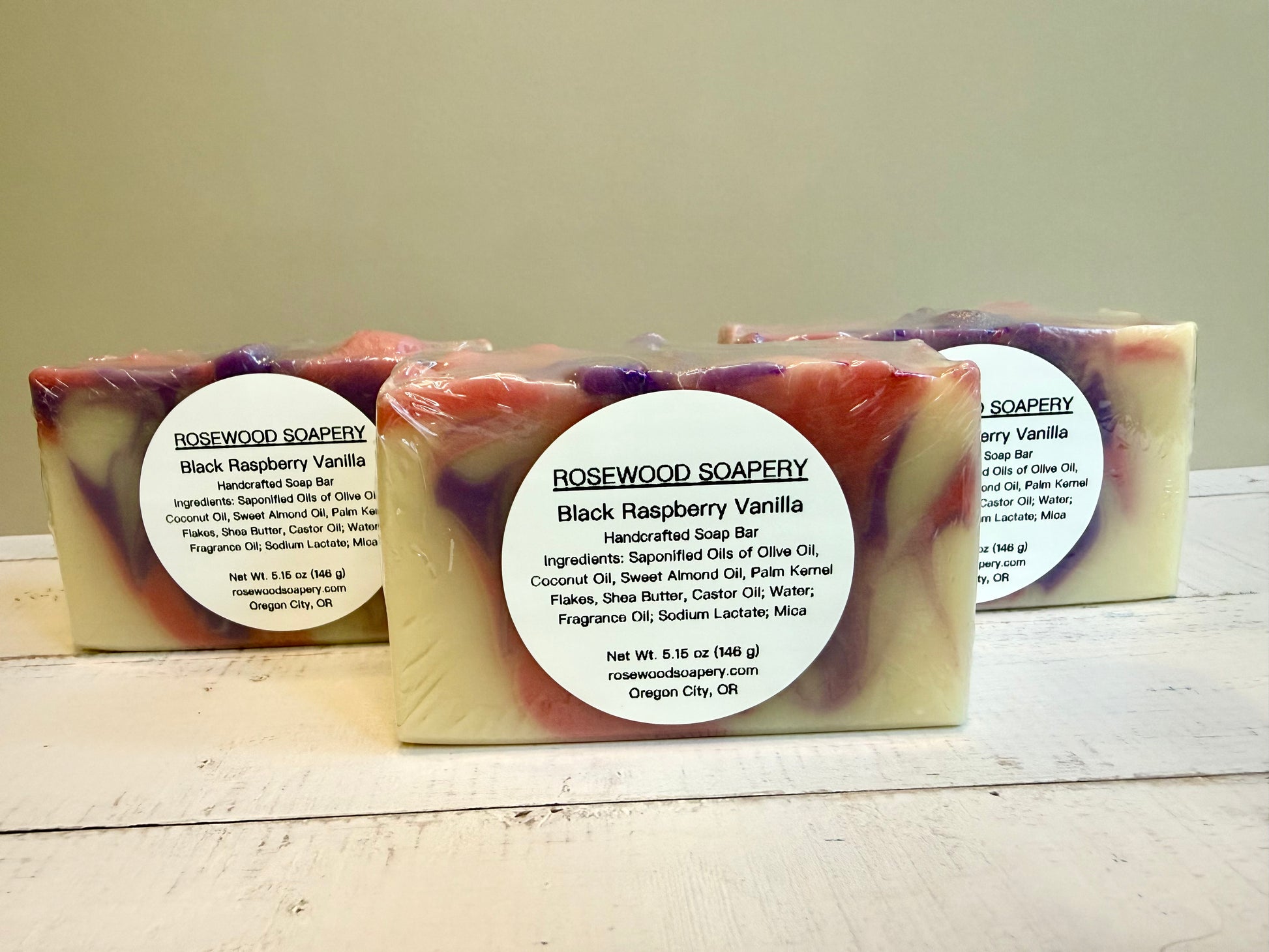 3 bars of soap with labels sitting on a wooden surface. 